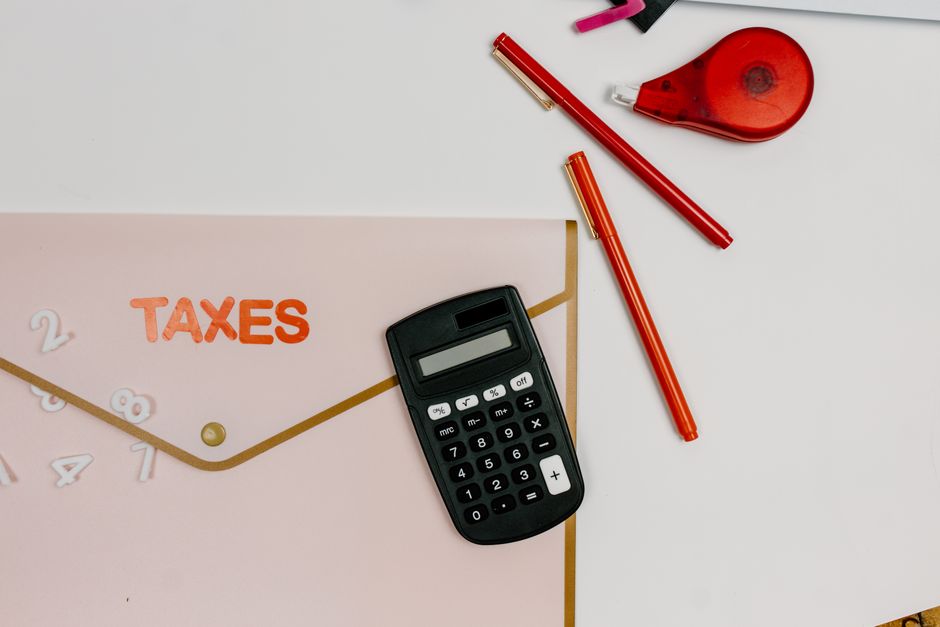 계산기, 펜, TAX라고 적힌 서류철이 놓인 책상